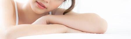 Portrait beautiful young asian woman smile while wake up healthy and wellness at morning on bed, beauty asia girl happy lying skin care and makeup cosmetic at bedroom, lifestyle and relax concept.の写真素材