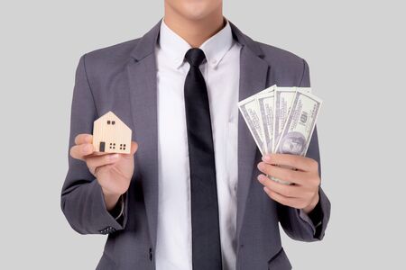 Young asian business man holding home and money dollar for saving for future, insurance agent and credit, debt and loan of finance, purchase home and refinance, investment about real property.の写真素材