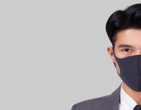 Portrait young asian businessman in suit wearing face mask for protective covid-19 isolated on white background, medical mask and healthcare, impact and quarantine for pandemic coronavirus.の写真素材