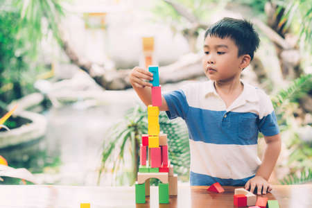 Asian young boy playing wooden block toy on table for creative and development with enjoy, happy child learn skill for activity puzzle and creativity for game on desk at home, education concept.の写真素材