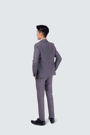 Rear view of young asian businessman in suit hand in pocket with confident isolated on white background, back of business man is manager or executive or employee thinking with success, full length.の写真素材