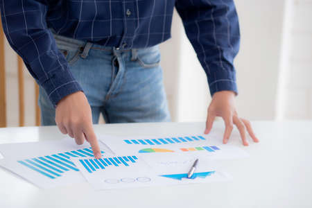 Hand of young business man pointing document data graph and chart paper, marketing and investment,...