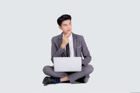 Young asian business man sitting thinking and work on laptop computer to internet online isolated on white background, businessman with notebook, freelance with success, marketing and communication.の写真素材