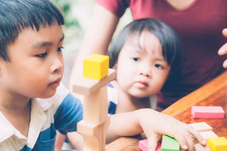 Family with asian mother and children playing toy block at home, mom and son and daughter doing activity and hobby about learning and development, creative and imagination, education concept.の写真素材