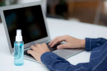 Hand of man work from home with alcohol gel or sanitizer for cleaning and protect coronavirus or covid-19, new normal, quarantine and social distancing, business and freelance using laptop computer.の写真素材