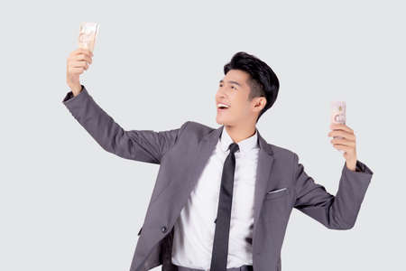 Young asian business man holding money Thai isolated on white background, businessman in suit holding banknote and success and excited with finance, savings and investment, income and spending.の写真素材