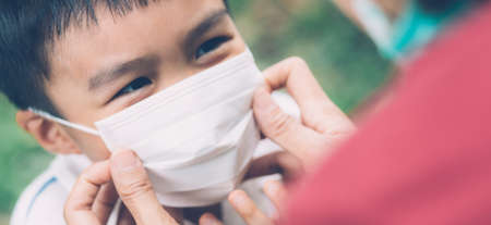 Mother take care son with face mask for protection disease flu or covid-19 outdoors, mom wearing on medical mask with child safety for protect outbreak of pandemic, medical concept, banner website.の写真素材