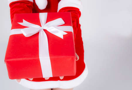 Closeup hand woman holding present box in xmas day with surprise isolated on white background, arm girl happy give red gift box with wrap paper and white ribbon in Christmas holiday or birthday.の写真素材
