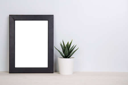 Mockup frame and plants in pot on table top at home, mock up poster for presentation on desk, indoor, your design for gallery photo and picture, border template and decoration for advertising.の写真素材