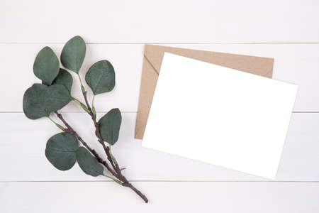 Blank paper sheet copy space with mockup and leaf on wooden table, card, poster and envelope,...