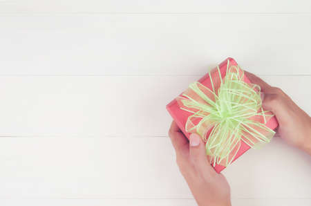 Hand of man holding gift giving on wooden table in Christmas day or holiday, present box for anniversary or birthday or celebration with copy space, celebrate and festive, top view, flat lay.の写真素材