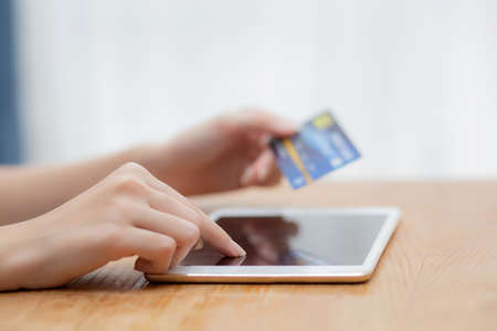 Closeup hand of young asian woman holding credit card shopping online with tablet computer blank...