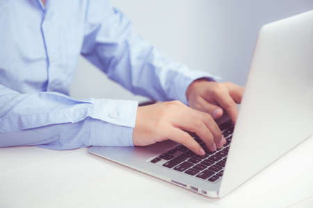 Hand of young man working on laptop computer on table at home office, male typing keyboard notebook...