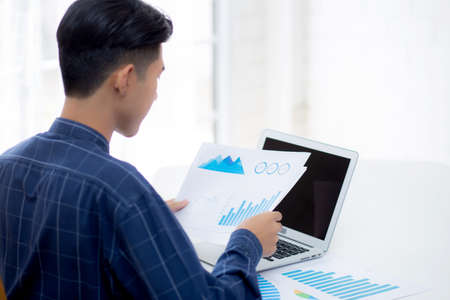 Hand of young business man looking document data graph and chart paper, marketing and investment,...
