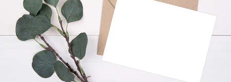 Blank paper sheet copy space with mockup and leaf on wooden table, card, poster and envelope, postcard decoration your design or branding, simplicity and minimal, flat lay, top view, banner website.の写真素材