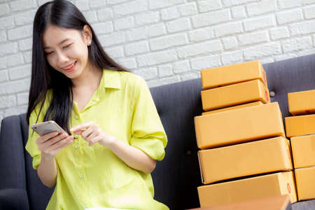 Young asian woman is entrepreneur check order from smartphone with customer while purchase online,...