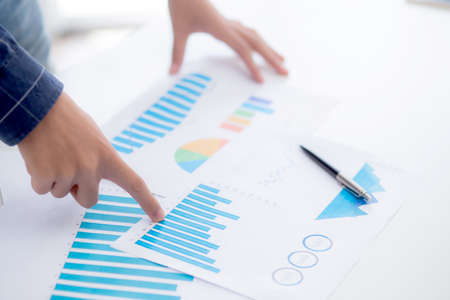 Hand of young business man pointing document data graph and chart paper, marketing and investment, report of statistics profit for financial, economic and growth of finance, management and planning.の写真素材