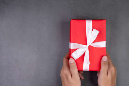 Hand of man holding gift giving on cement floor in Christmas day or holiday, present box for...
