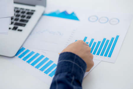Hand of young business man pointing document data graph and chart paper, marketing and investment,...