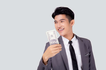 Young asian business man holding money dollar isolated on white background, businessman in suit holding banknote and success and excited with finance, savings and investment, income and spending.の写真素材