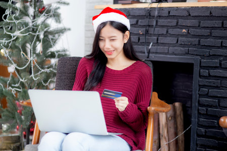 Young asian woman online shopping in Christmas with credit card on laptop computer, female buying and payment with debit card, xmas in holiday, happy new year, customer with purchase to internet.の写真素材