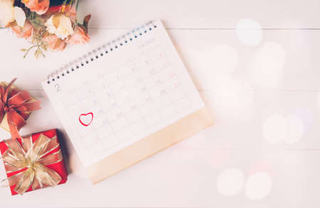 Calendar and flower with memo 14 February Valentine day on desk with blur bokeh background, reminder for surprise of love, romance and sweet, celebration and decoration, top view, holiday concept.の写真素材