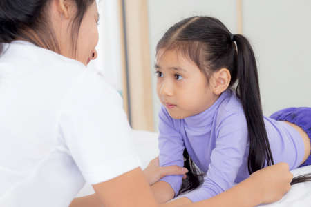 Young asian mom and daughter smiling and eye contact together with care in room, face of mother and girl looking eye with relationship and bonding, emotion and expression, family and love concept.の写真素材