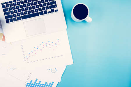 Laptop computer and documents report statistic financial with graph and chart and coffee on desk, finance and invest, digital marketing and growth of revenue, business and communication concept.の写真素材