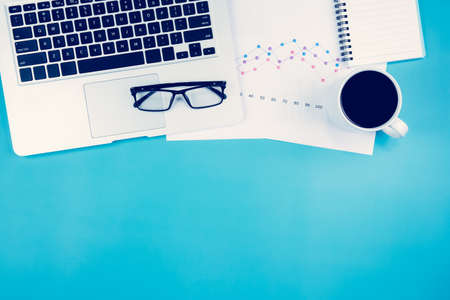 Laptop computer and documents report statistic financial with graph and chart and coffee and book...