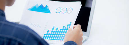Hand of young business man looking document data graph and chart paperの写真素材