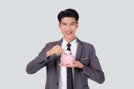 Young asian businessman in suit deposit money dollar with piggy bank isolated on white background, business man saving with planning budget and finance for success investment and financial.の写真素材
