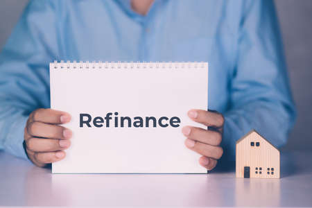 Hands of businessman holding refinance word on notebook and home model, finance and residential,...