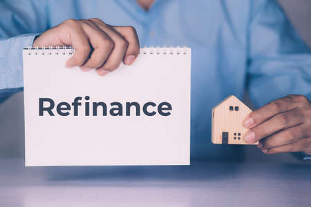 Hands of businessman holding home model and refinance word on notebook, finance and residential,...