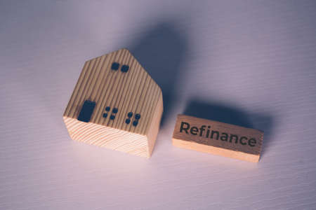 Wooden block with refinance word and house model about home and finance, loan and mortgage for real estate and property, residential and planning with budget, investment and earning, business concept.の写真素材