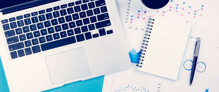 Laptop computer and documents report statistic financial with graph and chart and coffee and book, finance and invest, digital marketing and growth of revenue, business and communication concept.の写真素材
