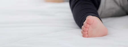 Closeup foot of asian little baby girl sleeping on bed in the bedroom at home, newborn napping with...