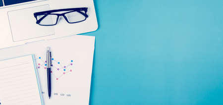 Laptop computer and documents report statistic financial with graph and chart and glasses and book, finance and invest, digital marketing and growth of revenue, business and communication concept.の写真素材