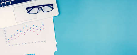 Laptop computer and documents report statistic financial with graph and chart and glasses on desk, finance and invest, digital marketing and growth of revenue, business and communication concept.の写真素材