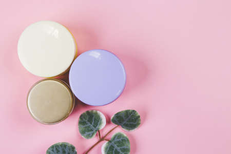Mockup cosmetic jar with cream or lotion and leaf isolated on pink background, mock up package for advertising, skincare or cosmetology, top view, flat lay, skin care and treatment with product.の写真素材