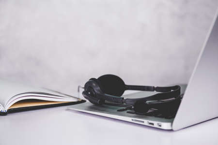 Laptop computer and headphone on desk, e-learning online, webinar for education and learning, seminar with notebook, video conference, headset for multimedia, course and classroom to internet.の写真素材