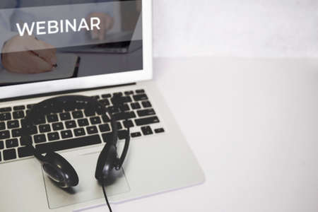 Laptop computer and headphone on desk, e-learning online, webinar for education and learning, seminar with notebook, video conference, headset for multimedia, course and classroom to internet.の写真素材