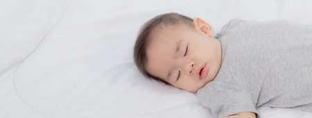 Portrait of asian little baby girl sleeping on bed in the bedroom at home, newborn napping with cozy and relax, infant innocence in bedtime, happy toddler cute, growth of child and emotion, indoors.の写真素材