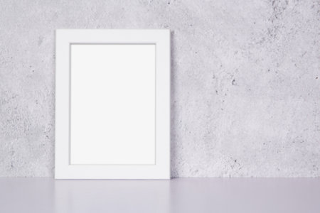 Mockup white frame vertical on table top and wall at home, mock up poster for presentation on desk, your design for gallery photo and picture image, border template and decoration for advertising.の写真素材