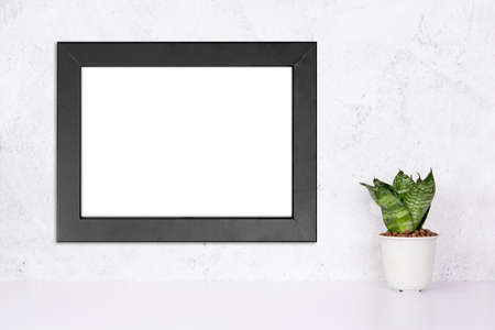 Mockup black frame horizontal on the wall and plants in pot on table top at home, mock up poster for presentation on desk, your design for gallery photo and picture, border template for advertising.の写真素材