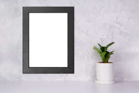 Mockup black frame vertical on the wall and plants in pot on table top at home, mock up poster for presentation on desk, your design for gallery photo and picture, border template for advertising.の写真素材