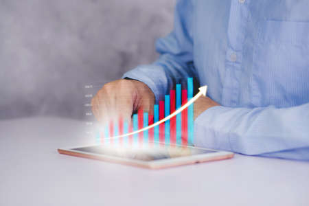 Businessman touch tablet computer with graph and chart of investment and finance, growth of stock and profit, digital marketing, planning of financial and target, business and communication concepts.の写真素材
