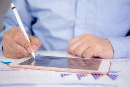 Businessman planning about graph and chart of investment with report for finance on tablet computer...