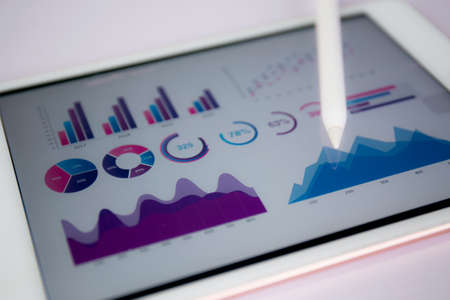 Report graph and chart of investment with finance on tablet computer on desk, datum of stock and growth, planning and statistic with economic, no people, digital marketing, business concept.の写真素材