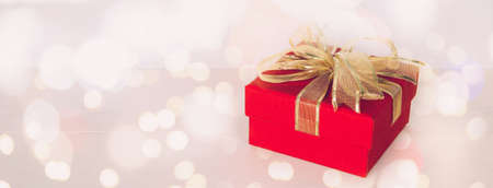 Red gift box on wooden table with bokeh background, love and romance, presents in celebration and anniversary with surprise on desk, happy birthday, copy space, nobody, valentine day concept.の写真素材