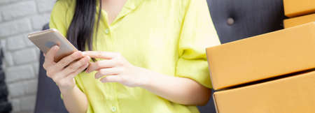 Young asian woman is entrepreneur check order from smartphone with customer while purchase online,...